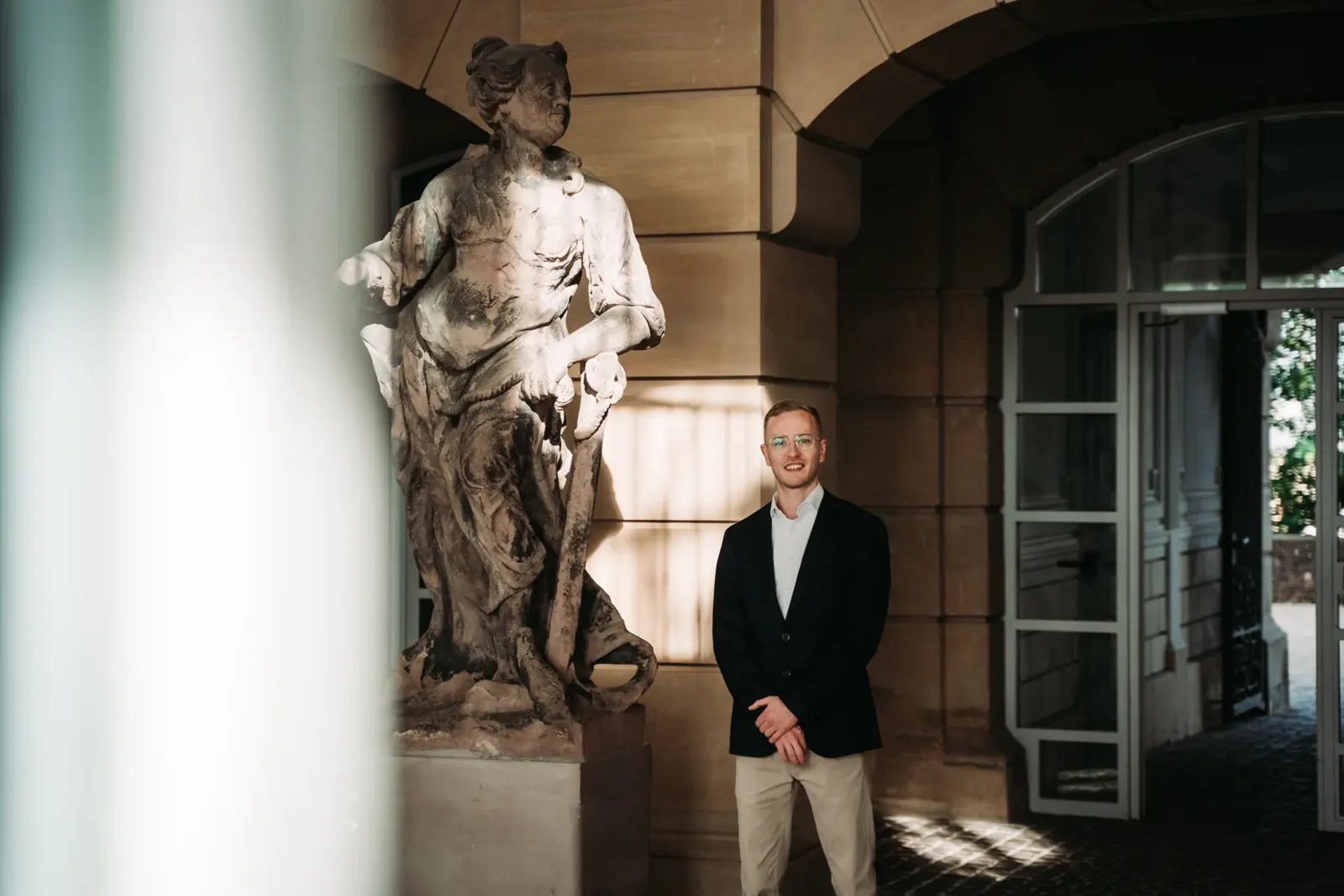 Jannik Trenz in a suit beneath a historic archway