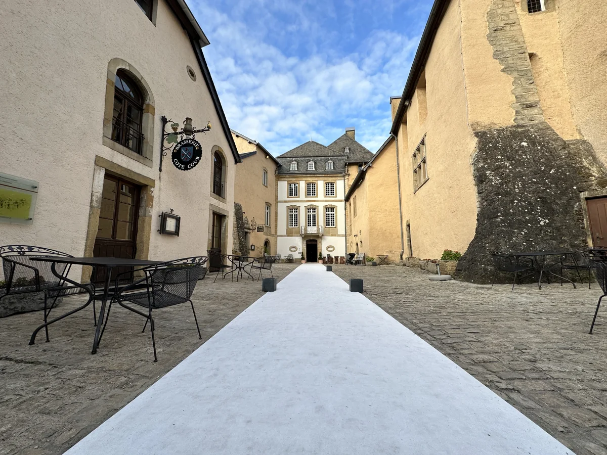 Cour du Château de Bourglinster avec un tapis blanc entre les bâtiments historiques