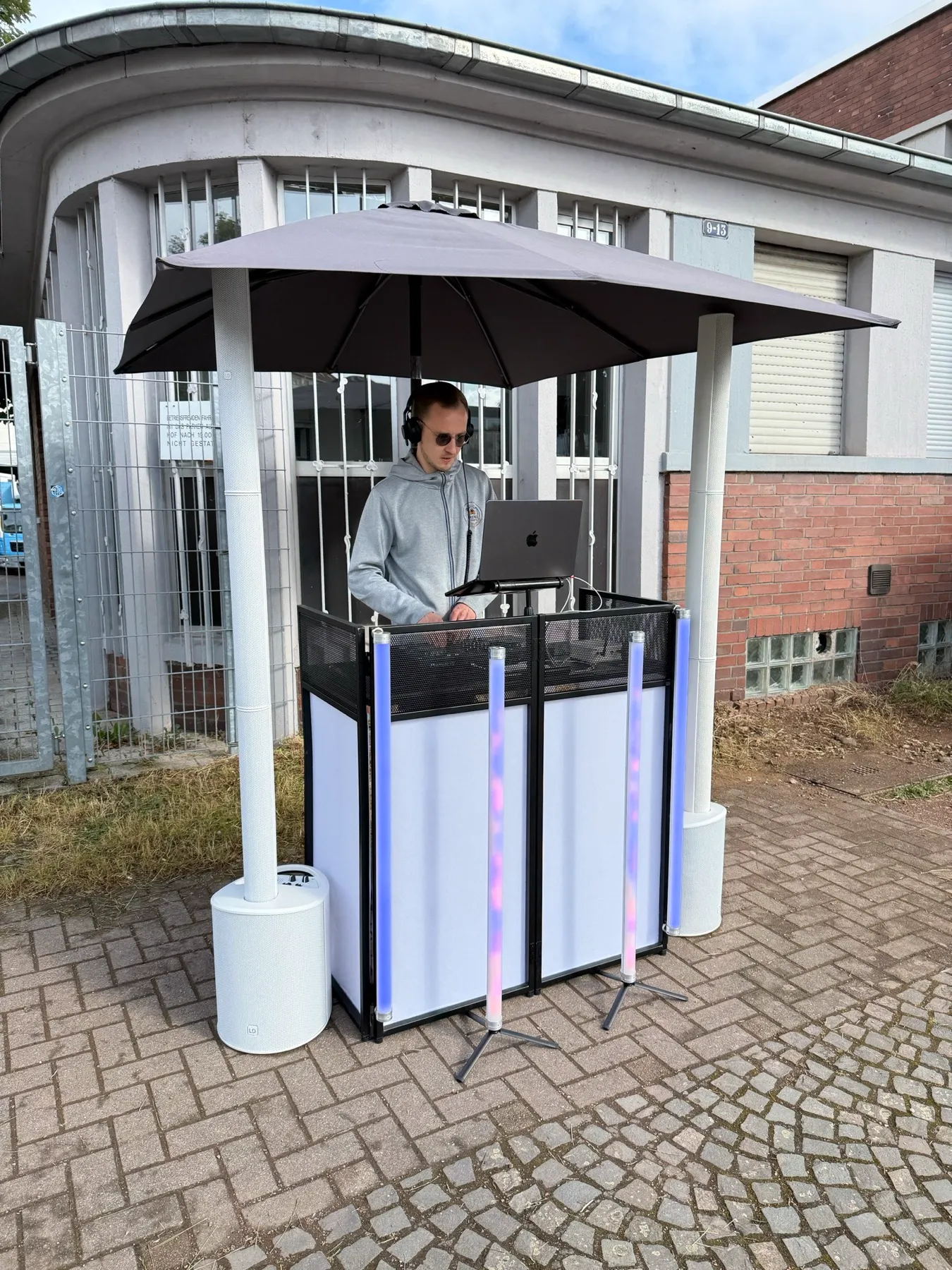 Weißes Akku-Pult mit Sonnenschirm und Lichtstäben an der Strecke eines Firmenlaufs