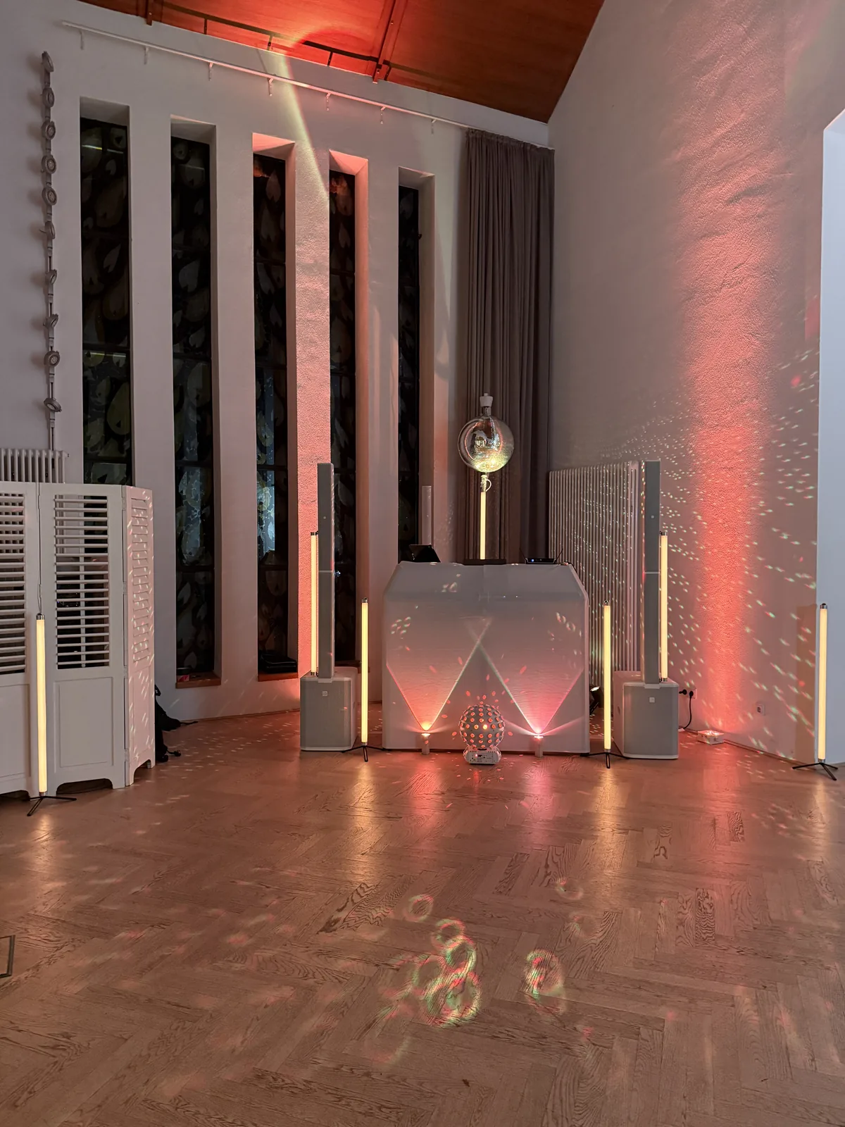 Mein weißes DJ-Setup mit Spiegelkugel und roten Lichtakzenten im hohen Saal des Klosterhotels Marienhöh in Langweiler